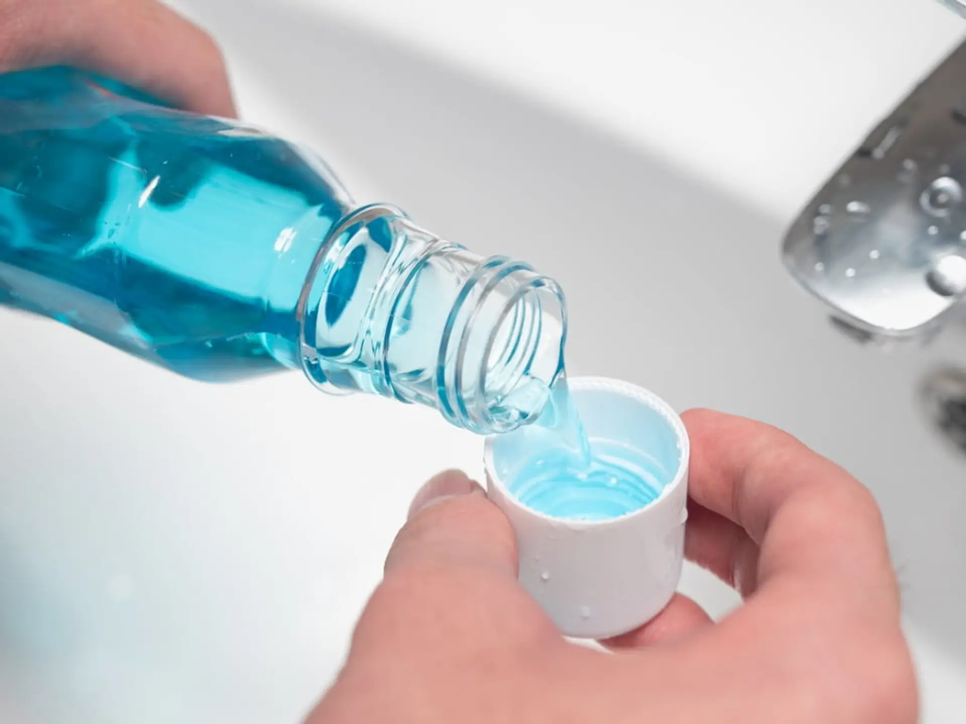 hands pouring mouthwash into cap