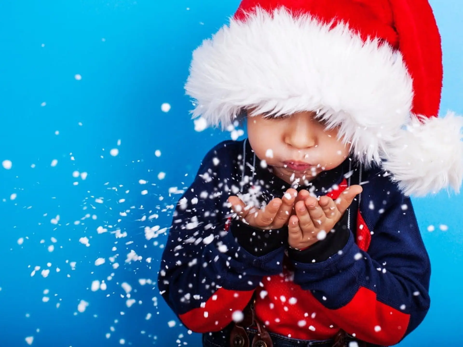 young boy blowing snowflakes