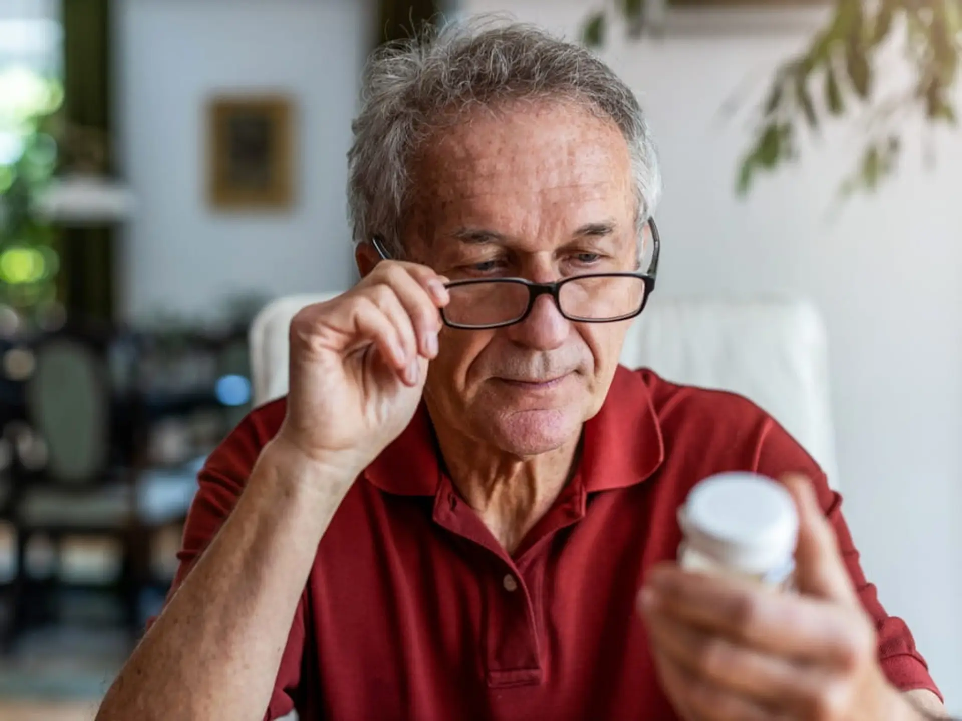 elderly man reading medicine bottle