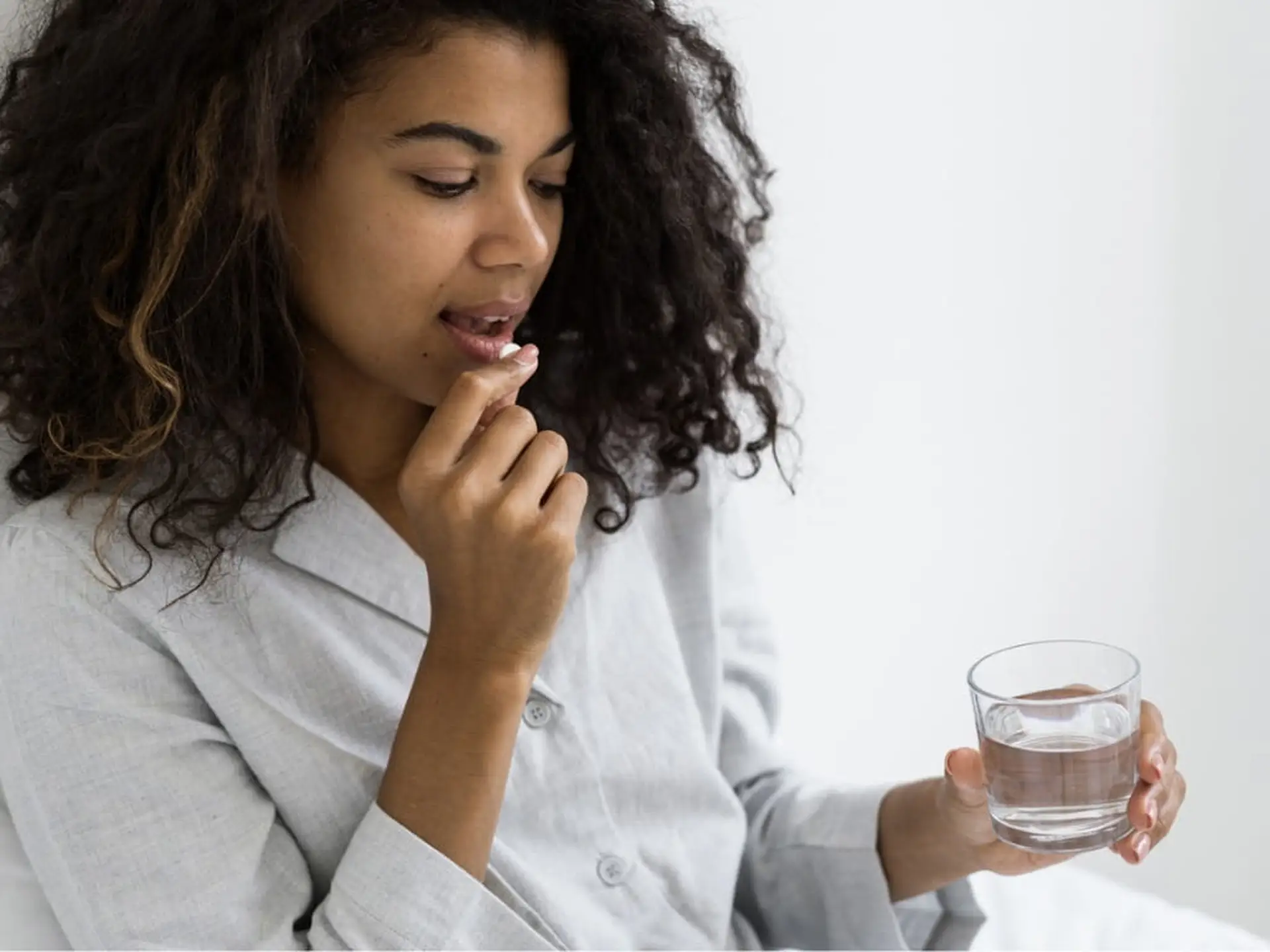 woman taking a pill and holding a glass of water