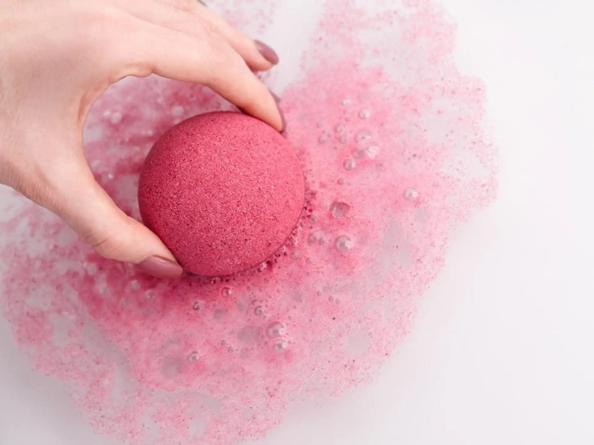 woman putting bath bomb into water