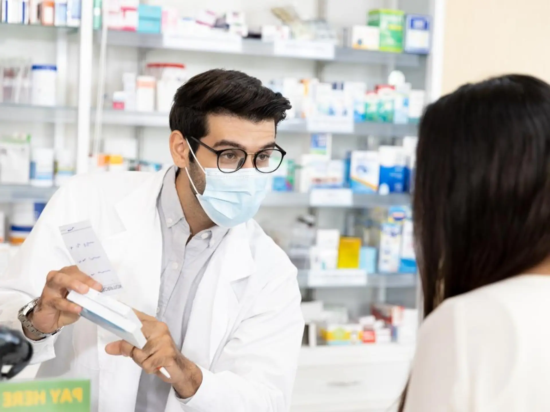 pharmacist wearing a mask showing a medication