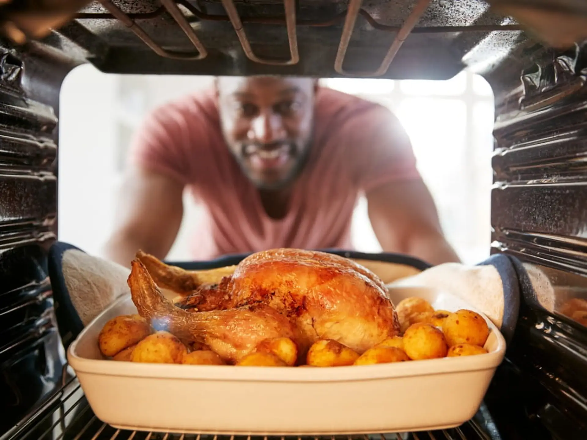 man taking chicken out of the oven
