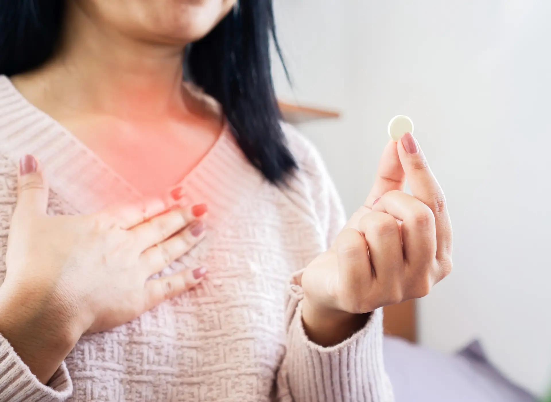 woman with heartburn holding a pill