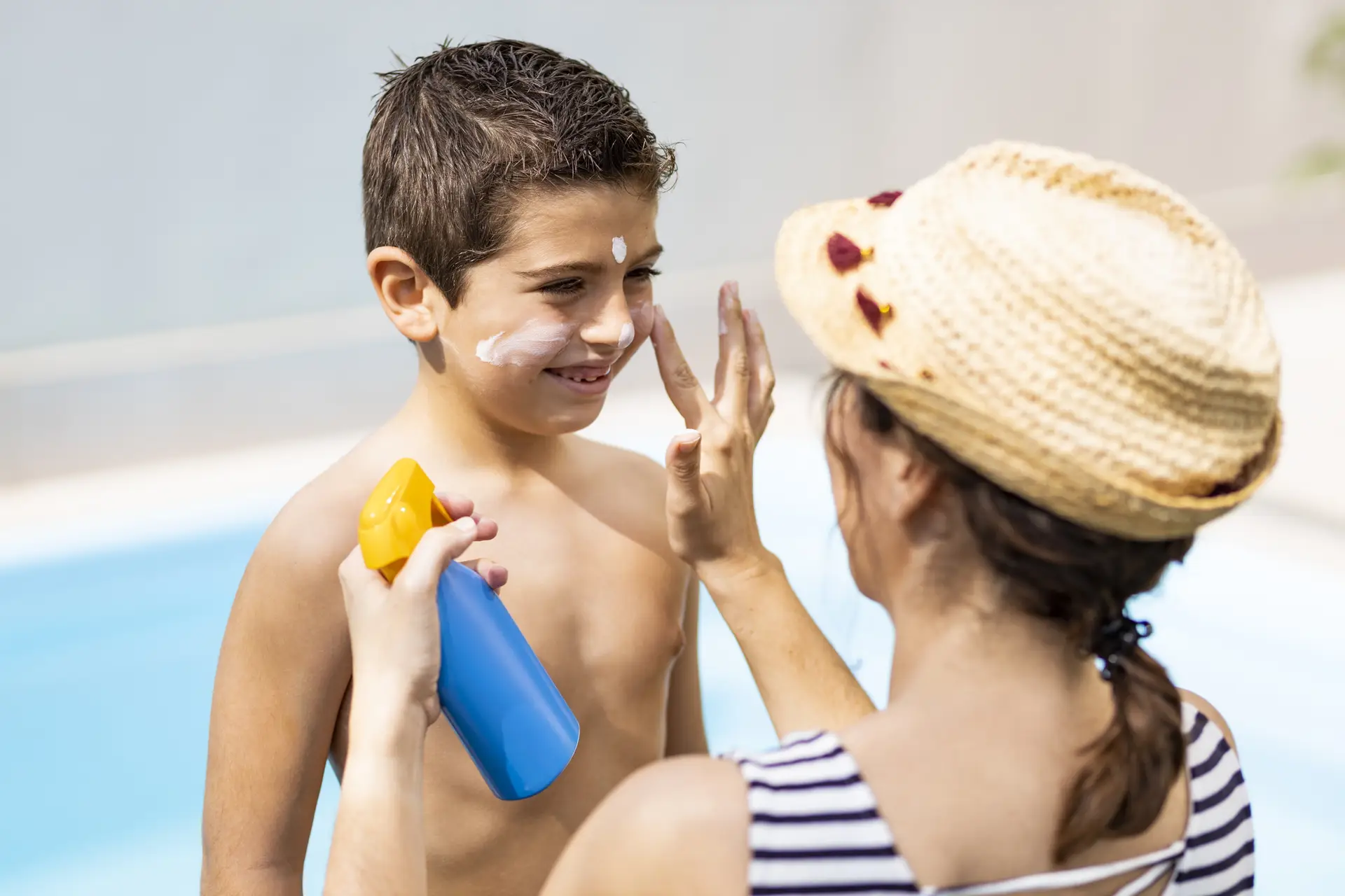 mother applies sunscreen to her son