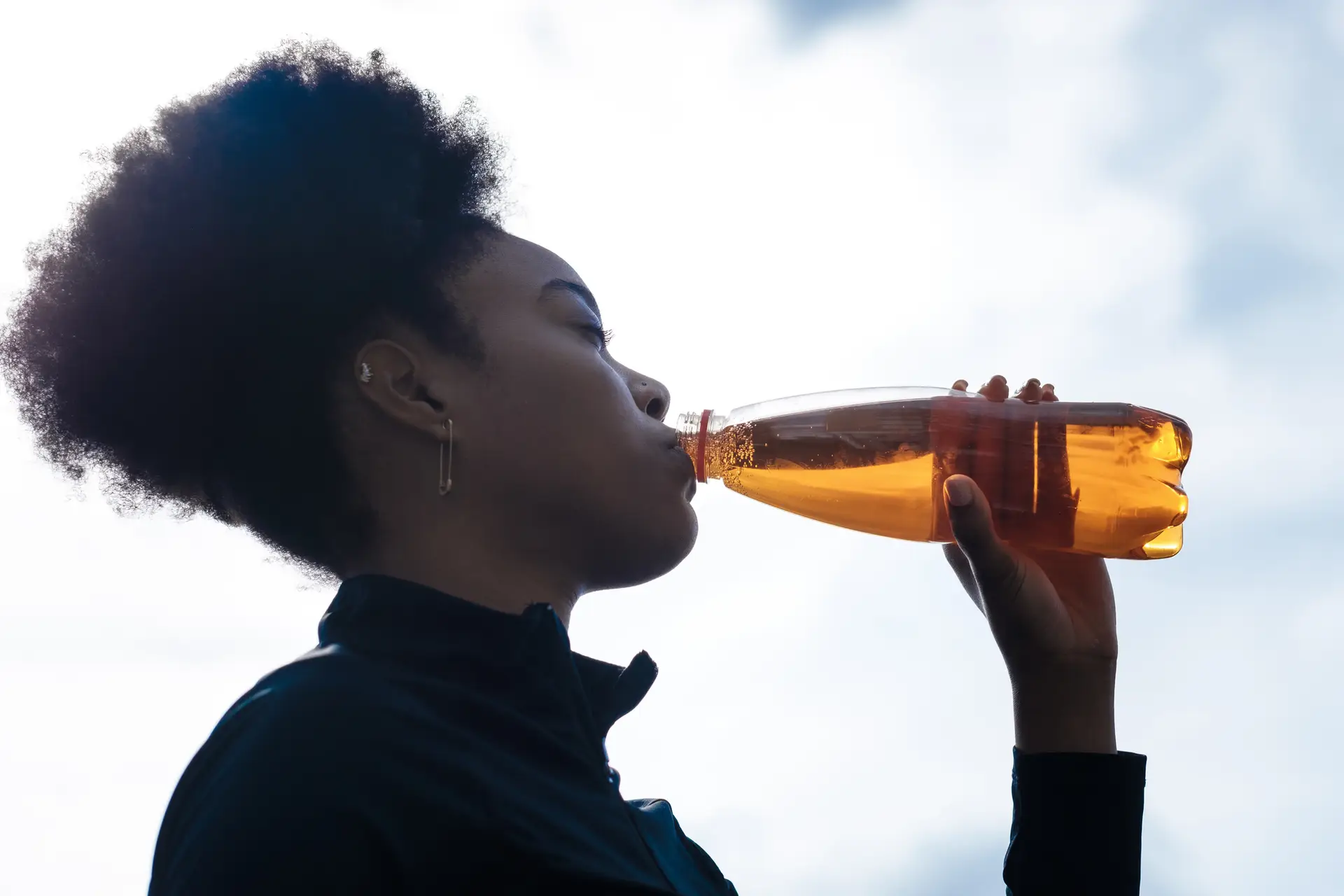 woman drinking colored liquid from a bottle