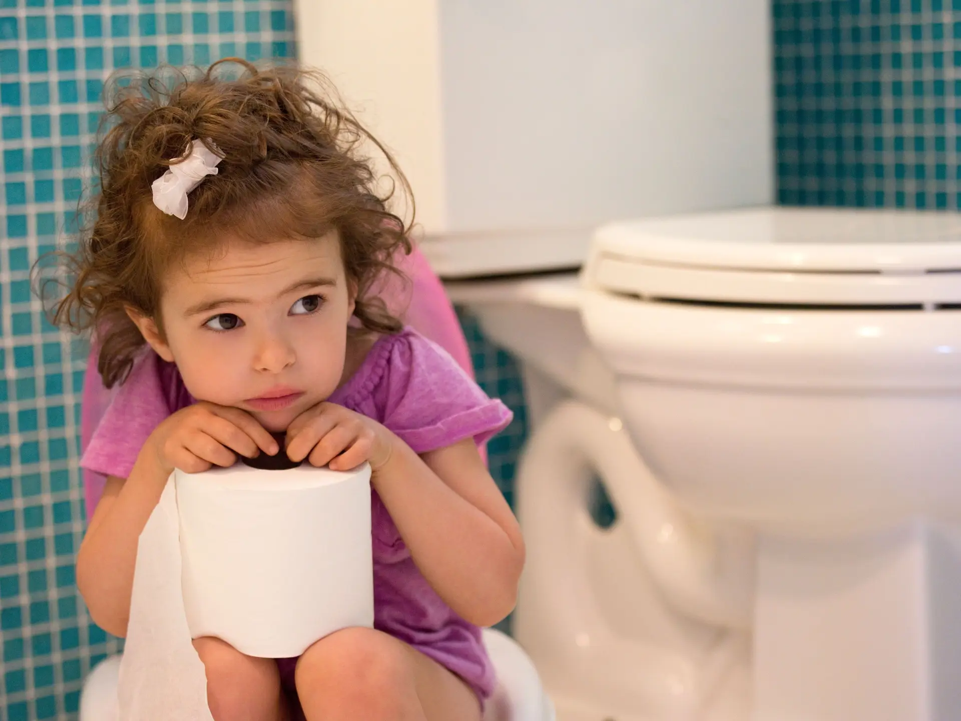 Girl on toilet with toilet paper
