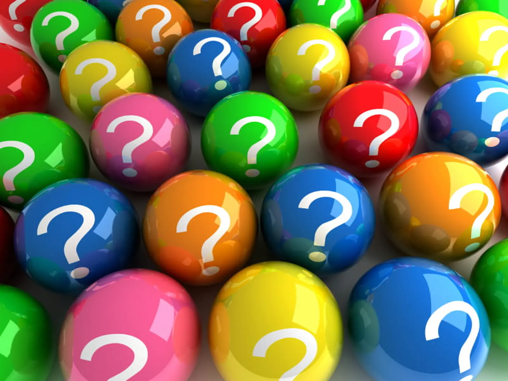 Colorful spheres with white question marks on them, arranged closely together, creating a vibrant and playful pattern.